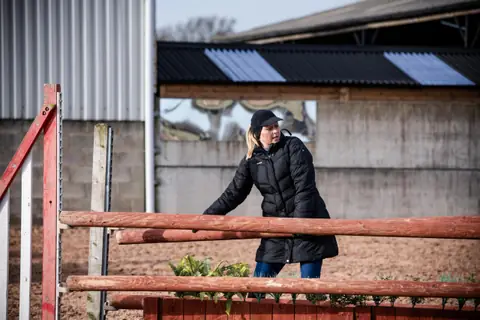 Coach adjusting a fence pole in an arena