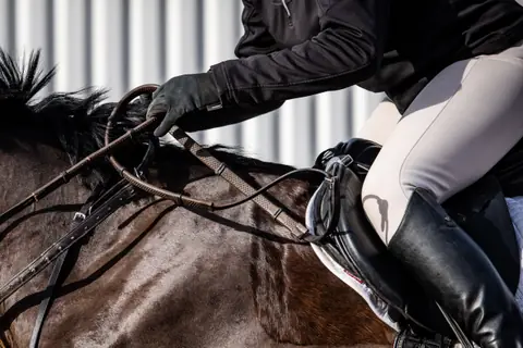 Close up of a rider’s hands, reins and saddle