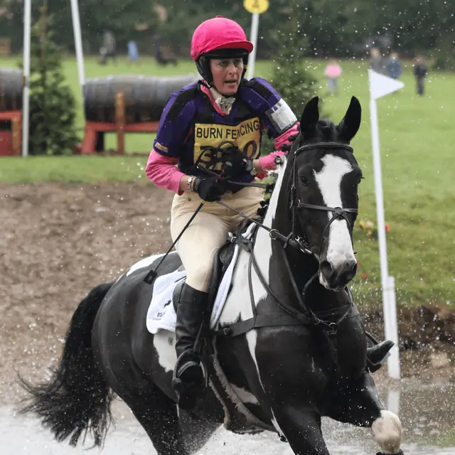 Rider in purple silks on a skewbald horse at a cross country water jump